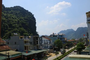 A town with buildings, a road, and a mountain in the background. - Thien Phu Hostel (Phong Nha)