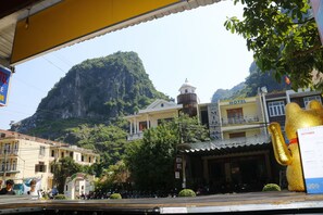 A hotel with a mountain backdrop, a bell tower, and a golden statue. - Thien Phu Hostel (Phong Nha)