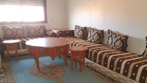A living room with a sofa set, a round wooden coffee table, and two small side tables.