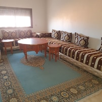 A living room with a sofa set, a round wooden coffee table, and two small side tables.