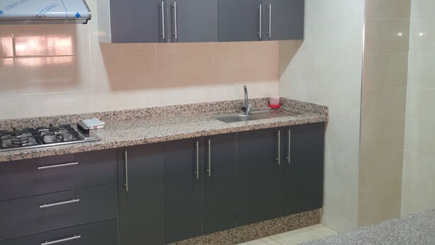 A kitchen with dark cabinets, a granite countertop, a gas stove, and a sink.