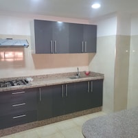 A kitchen with dark cabinets, a granite countertop, a gas stove, and a sink.