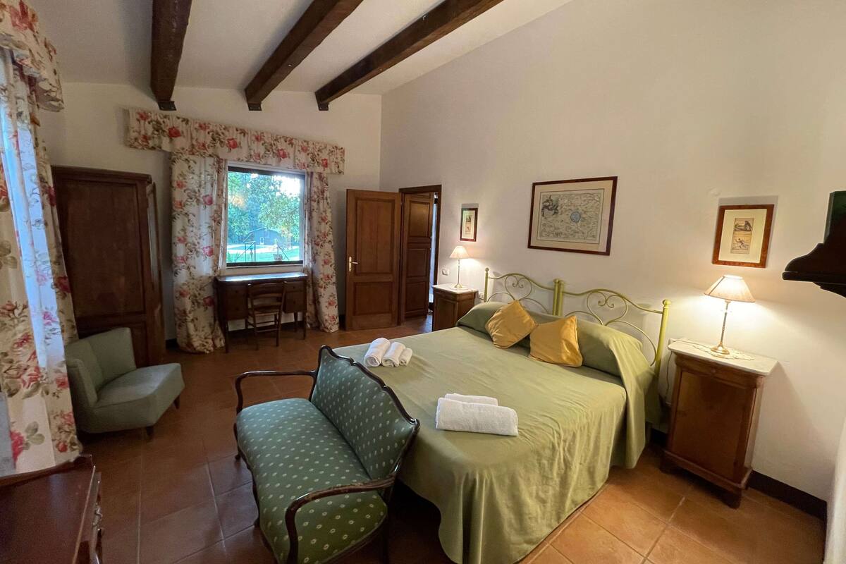 A bedroom with a bed, a desk, a chair, and a window.