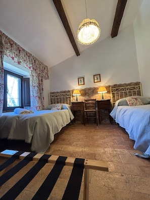 A cozy room with two beds, a wooden table, and a stone wall. - Castello di Santa Cristina (Grotte di Castro)