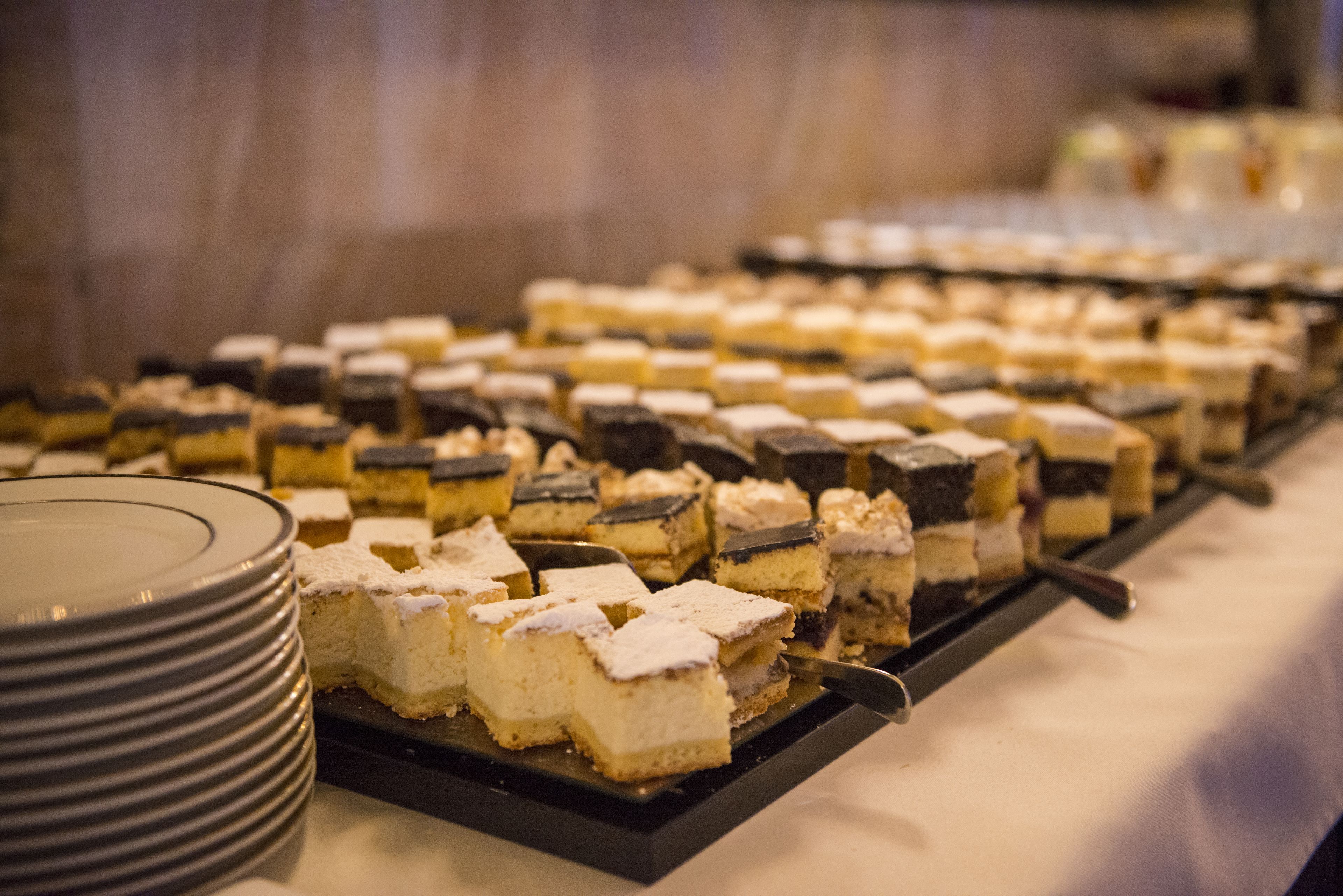 A buffet table with neatly arranged square desserts.