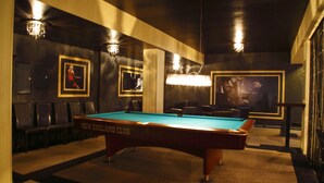 A pool table labeled "NEW ENGLAND CLUB" in a dimly lit room with framed pictures on the walls and a chandelier. - Hotel Iskierka Business & Spa (Mielec)