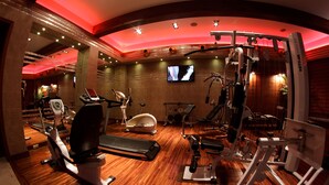 A gym with various exercise equipment, a television, and a wooden floor. - Hotel Iskierka Business & Spa (Mielec)