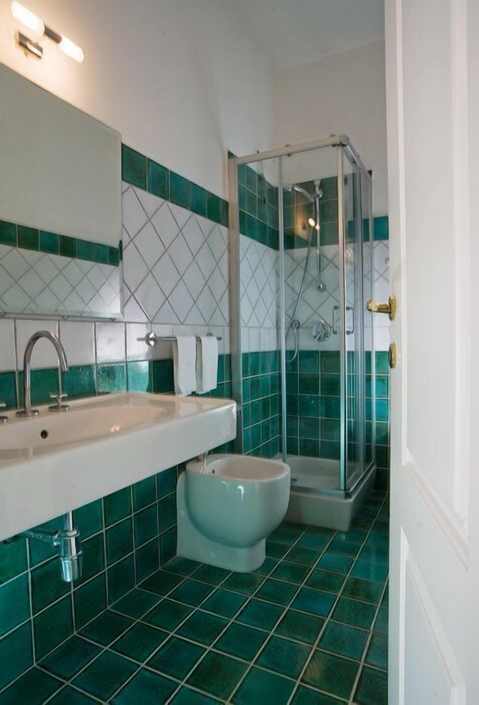 A bathroom with a white sink, a toilet, and a glass-enclosed shower.