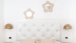 A bedroom with a tufted headboard, two bedside tables with decorative lamps, and two wall-mounted mirrors. - B&B Il Sogno (Anacapri)