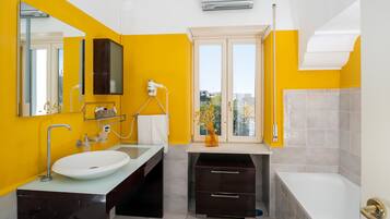 Un baño moderno con una paleta de colores amarillo y blanco, que incluye un lavamanos, tocador y bañera.