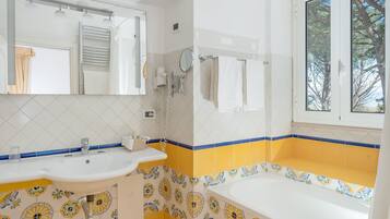 Un baño con lavamanos, espejo, toallero y bañera.