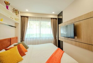 A hotel room with a bed, a television mounted on the wall, and a window with curtains.