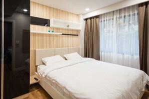 Un dormitorio moderno con una cama grande, estanterías empotradas y vistas al exterior a través de cortinas de gasa.