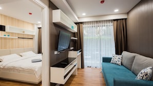 Una habitación de hotel moderna con una cama, un televisor, un sofá y una ventana con cortinas.
