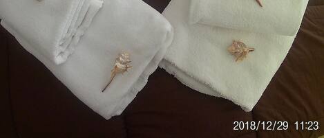 Dos toallas blancas con conchas marinas sobre un sofá marrón.
