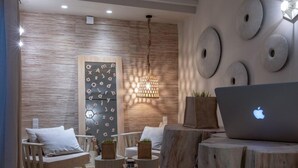 A modern living room with a wooden floor, a sofa, a chair, a wooden table, and a laptop. - Oniro Suites (Mykonos)
