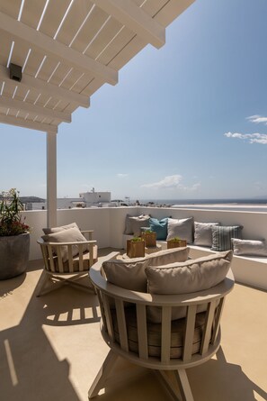 Une terrasse avec deux chaises en bois, un plafond blanc et une vue sur la mer.