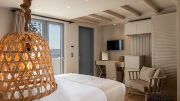 A modern hotel room with a large bed, a desk, a chair, a television, and a wardrobe.