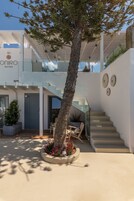 Un hotel moderno con una struttura a due piani, una scala in vetro e un albero nel cortile.