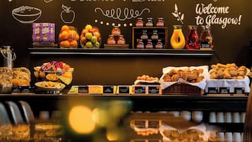 A breakfast buffet with various food items and beverages, including fruits, pastries, and condiments.