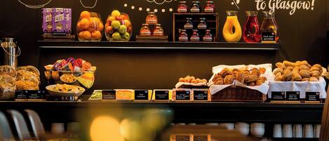 Un buffet de petit-déjeuner proposant une variété d’aliments et de boissons, notamment des fruits, des viennoiseries et des condiments.
