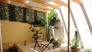 A small outdoor seating area with a table and chairs, surrounded by potted plants and a decorative wall. - Zefiro Rooms & Breakfast (San Vito Lo Capo)