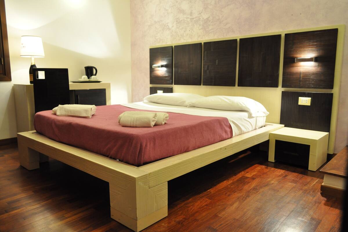 Un dormitorio moderno con una cama de madera, una mesita de noche y una lámpara.