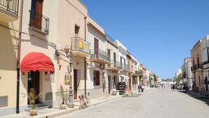 A street with buildings, a red awning, and a bicycle. - Zefiro Rooms & Breakfast (San Vito Lo Capo)