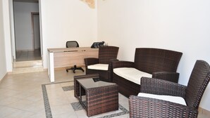 A furnished room with a desk, wicker furniture, and a tiled floor. - Zefiro Rooms & Breakfast (San Vito Lo Capo)