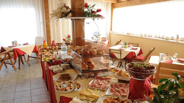 A buffet with various food items, including pastries, meats, and cheeses, arranged on tables with red tablecloths. - Zefiro Rooms & Breakfast (San Vito Lo Capo)