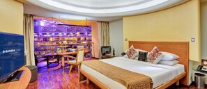 Une chambre d’hôtel avec un grand lit, un bureau avec une chaise, une télévision et un minibar.