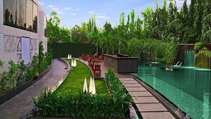 A swimming pool with a curved pathway, seating area, and lush greenery. - Sahara Star (Mumbai)