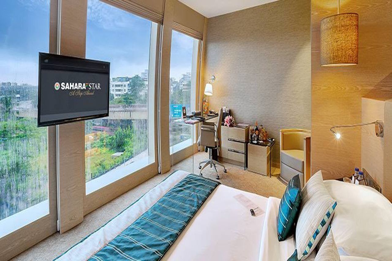 Une chambre d’hôtel avec un lit, un bureau, une chaise, une télévision et une vue sur la ville.