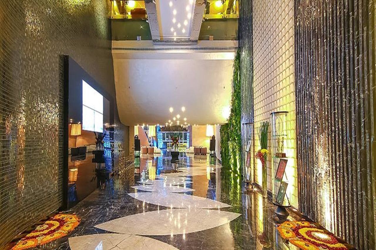 Vestíbulo de hotel con piso reflectante, una recepción y un ventanal grande.