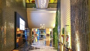A hotel lobby with a reflective floor, a reception desk, and a large window. - Sahara Star (Mumbai)