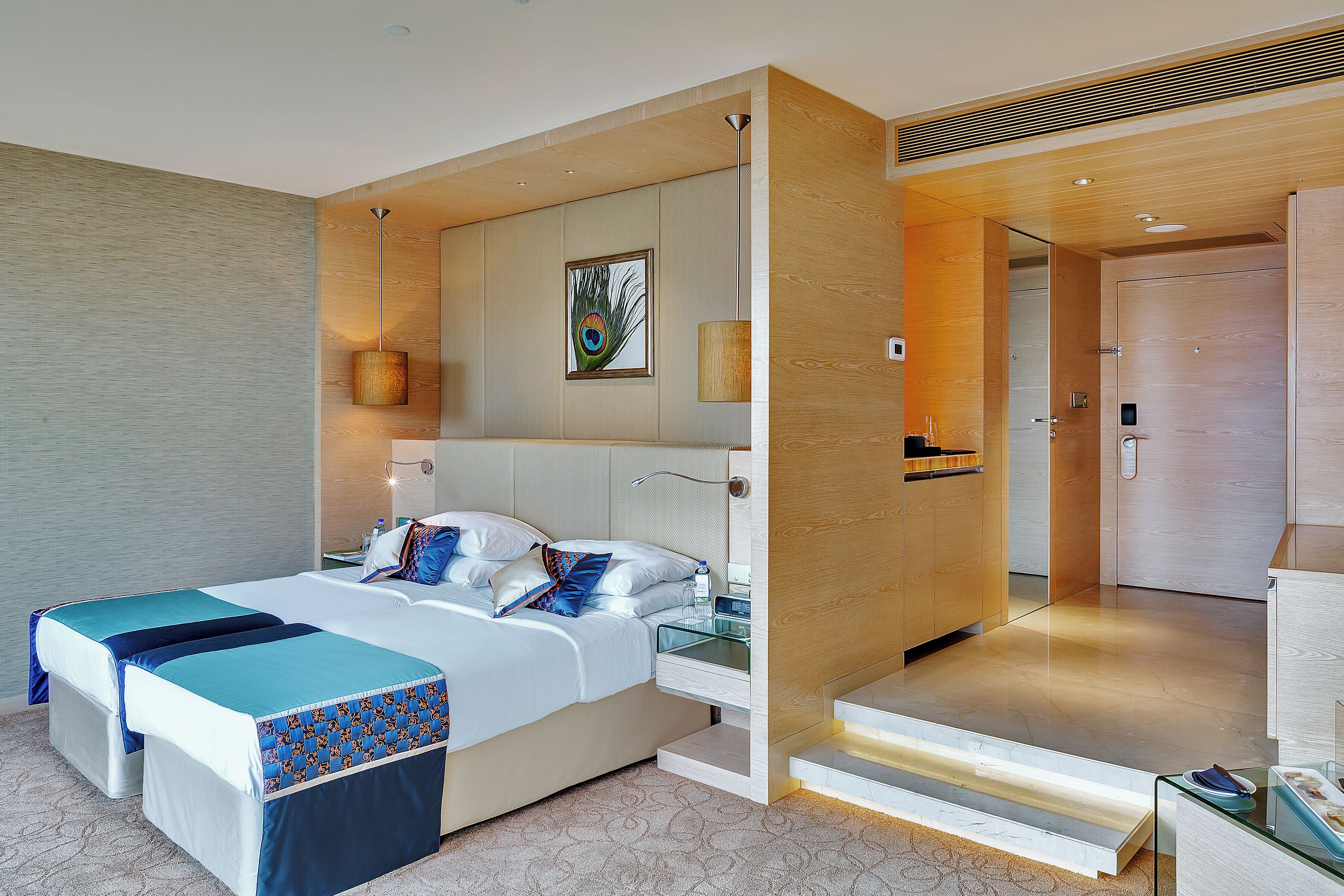 A modern hotel room with a large bed, bedside tables, a mirror, and a door leading to a bathroom.