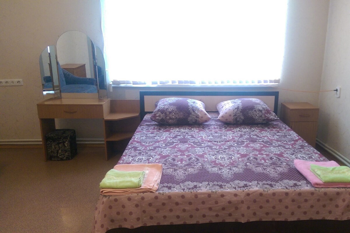 Une chambre à coucher avec un lit, une commode, un miroir et une fenêtre.
