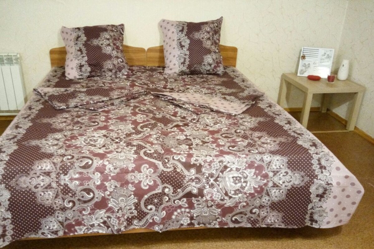 Une chambre à coucher avec un grand lit, deux oreillers, une table de chevet avec une lampe et un radiateur.