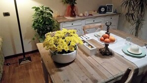 A dining table with a floral centerpiece, a fruit bowl, and a vintage clock. - B&B Lake Como Cottage (Lecco)