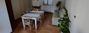 A dining area with a wooden table and chairs, a fireplace, a radiator, and a sofa. - B&B Lake Como Cottage (Lecco)