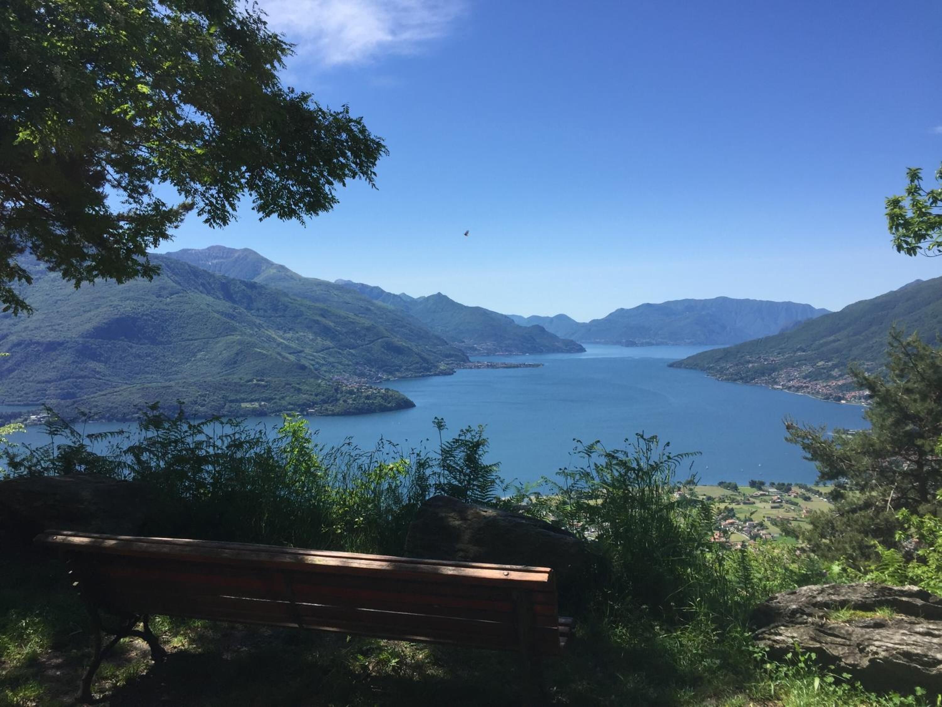 A bench overlooking a lake surrounded by mountains.
