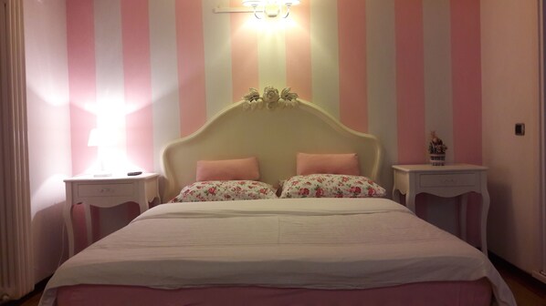 A bedroom with a bed, two nightstands, a lamp, and a wall with vertical stripes. - B&B Lake Como Cottage (Lecco)