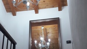 A wooden ceiling with a chandelier and a large mirror reflecting the room. - B&B Lake Como Cottage (Lecco)