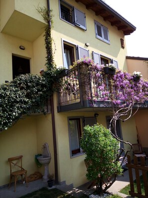 A two-story building with a balcony adorned with purple flowers and climbing plants. - B&B Lake Como Cottage (Lecco)