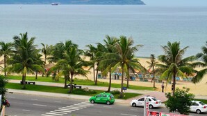 Una carretera frente a la playa, con palmeras y vista al mar.
