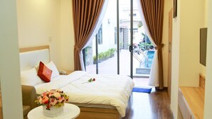 Habitación de hotel con cama, una mesita redonda con un florero y vistas al exterior a través de un ventanal.