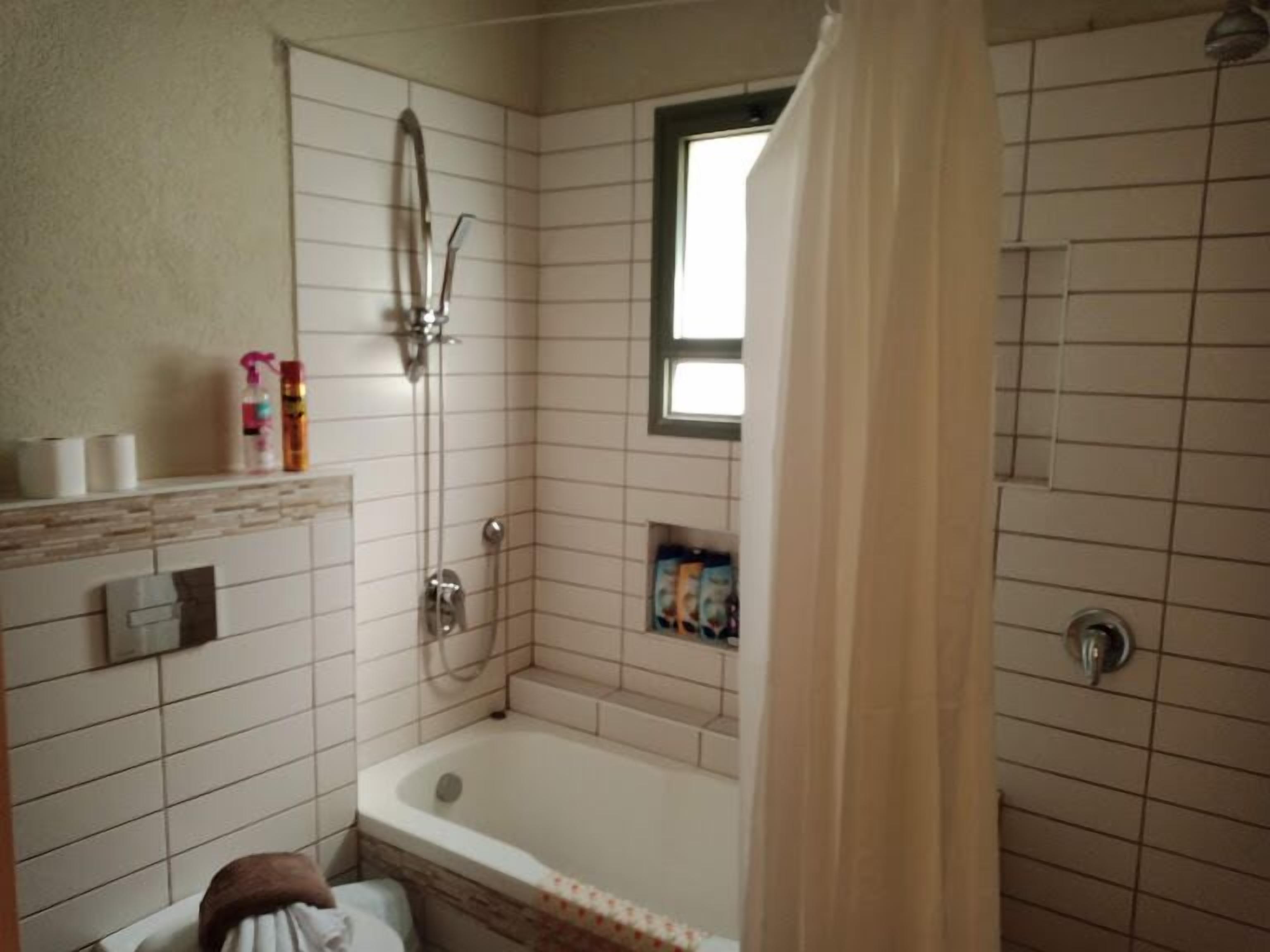 A bathroom with a bathtub, a shower, and a window.