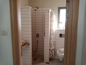 Un baño con ducha, inodoro y un perchero para toallas.