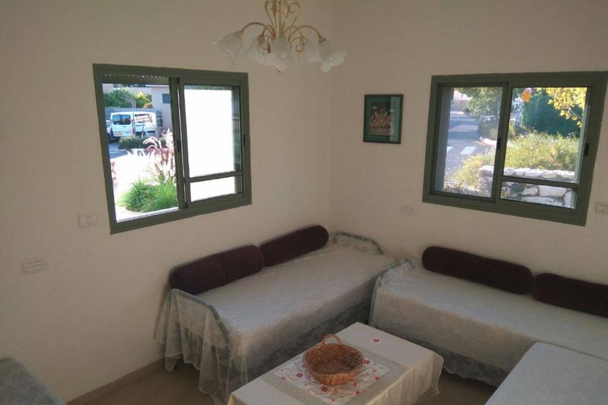 Une petite chambre agréable, dotée de deux lits simples, d’une table avec un panier, et de deux fenêtres donnant sur l’extérieur.