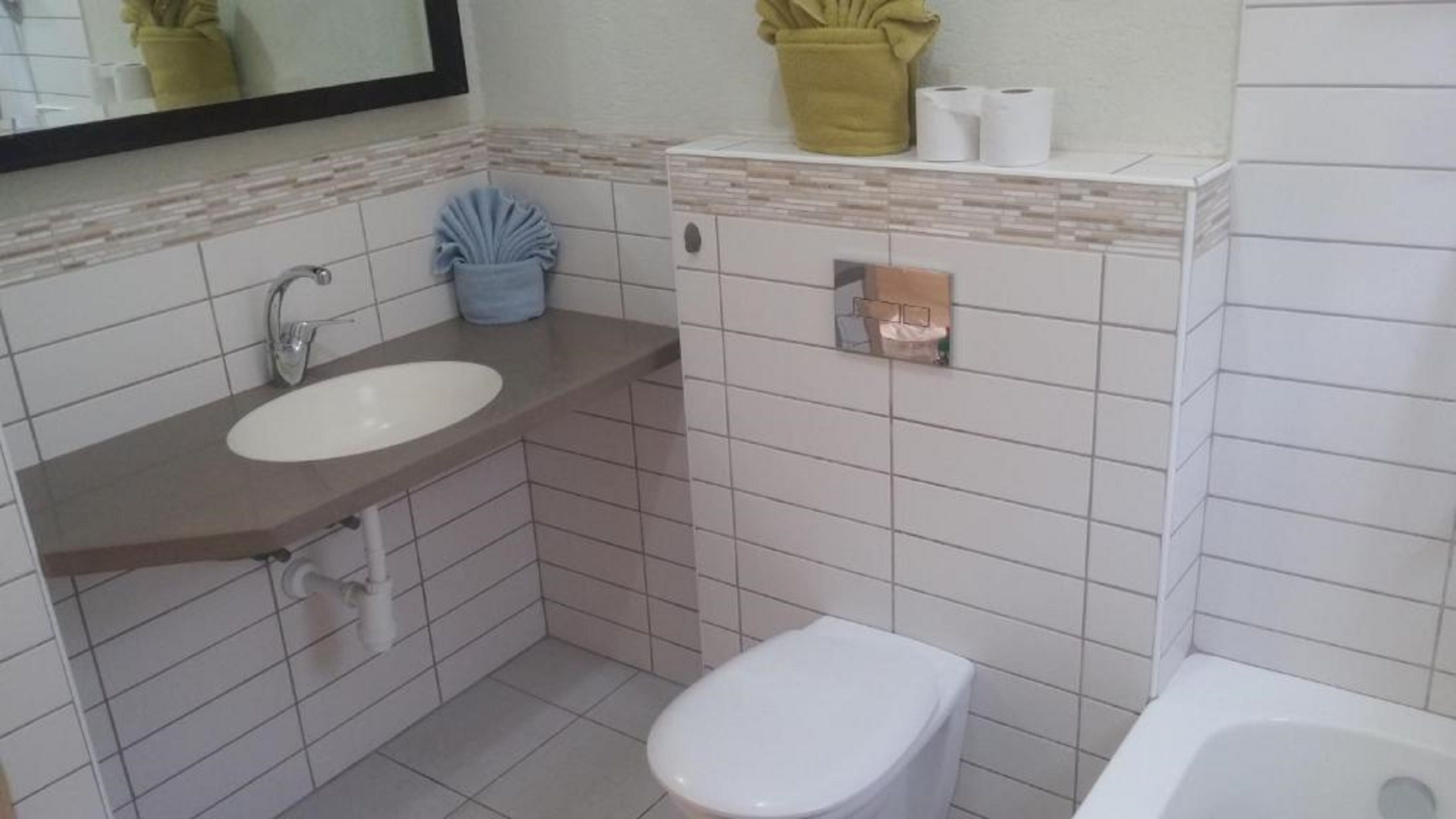 A small bathroom with a white sink, a toilet, and a bathtub. There is a mirror above the sink and a towel rack with towels.